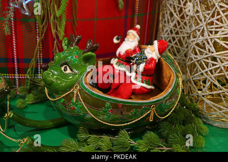 Zwei Santa Claus reiten Green Rentier geformten Schlitten, eine einzigartige Weihnachten Dekoration Stockfoto