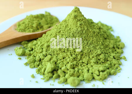 In der Nähe der pulsierenden grünen Farbe Matcha Tee Pulver, Zutat für heiße Grüner Tee mit unscharfen Holzlöffel im Hintergrund Stockfoto
