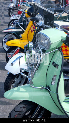 Die Vorderräder und Bars und Scheinwerfer von sieben Mopeds oder Roller in einer Linie Reduzierung in der Perspektive bearbeiten Stockfoto