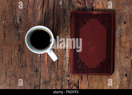 Kaffeetasse und altes Buch auf dem hölzernen Tisch