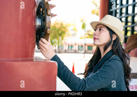 Attraktive asiatische Frau bewundern und berühren die hölzerne Skulptur friedlich in japanischen Schrein. Stockfoto