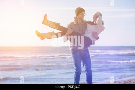Junges Paar, das Spaß am Wandern und umarmen am Strand im Herbst sonniger Tag Stockfoto