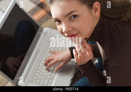 Blick von oben auf die junge Teen Girl couch bereitet Bericht über die Lektion, korrigiert Fehler, Tastaturen auf Laptop, sucht Informationen. Student d Stockfoto