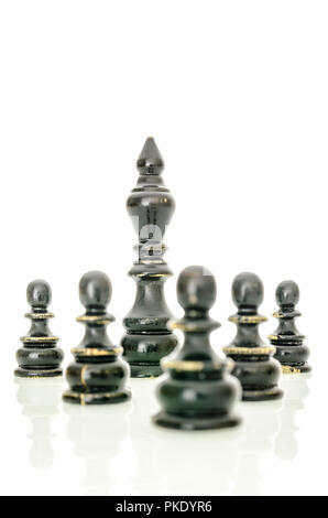 Alte schwarze Schachfiguren. König geschützt durch die Bauern. Auf weissem Hintergrund. Stockfoto