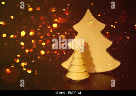 Kreative Holz- Weihnachtsbaum Spielzeug mit Gold funkelnde Bokeh um im Dunkeln. Luxuriöse elegante Frohe Weihnachten und guten Rutsch ins neue Jahr Poster, Einladungskarte, mit leuchtenden Gold Schneeflocken Stockfoto