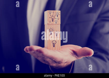 Unternehmer hält drei Holzwürfel vertikal ausgerichtet, mit handgezeichneten Glühlampen, Konzept der kreativen Ideen und neuen Business Projek Stockfoto