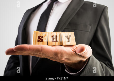 Geschäftsmann holding Holz- alphabet Bausteine lesen - schüchtern - in seiner Hand ausgeglichen. Stockfoto
