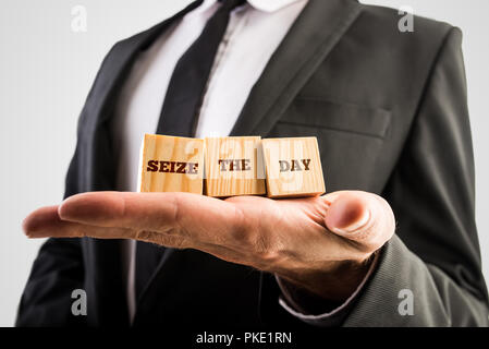 Unternehmer hält drei Holzwürfel oder Bausteine in die Hand mit den Worten - Nutze den Tag - in eine motivierende und inspirierende Stockfoto