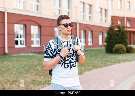 Junger stattlicher Mann mit Sonnenbrille und Tasche reisen an einem sonnigen Tag Stockfoto