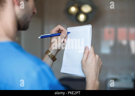 Arzt Chirurg schreiben in einem Notebook auf dem Hintergrund der Arbeitsscheinwerfer. Stockfoto