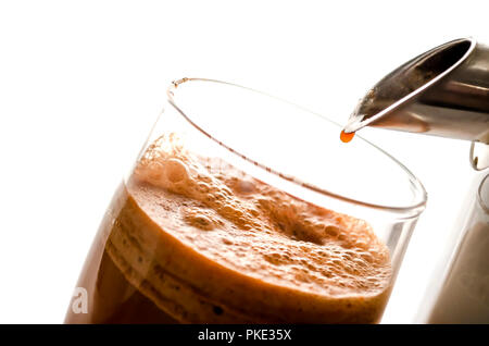 Nahaufnahme von frisch gepresster Karottensaft mit einem Entsafter. Auf einem weißen Hintergrund. Stockfoto