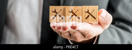 Close up Konzeptuelle Geschäftsmann, Holzklötze auf seiner Hand mit Service Tools Drucke. Stockfoto