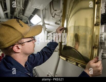 NORFOLK, Virginia (25. Juli 2018) Der Luftverkehr strukturellen Mechaniker 3. Klasse Kevin Bramblett, von Cleveland, Tennessee, strahlt Messing während der Reinigung Stationen an Bord der Flugzeugträger USS George H.W. Bush (CVN 77). Das Schiff ist im Hafen in Norfolk, Virginia, die Durchführung von routinemäßigen Übungen Träger bereit zu halten. Stockfoto