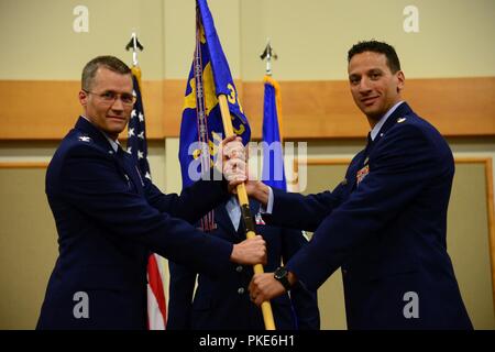 Maj Frank Schiavone, rechts, übernimmt das Kommando über die 341. öffentliche Auftraggeber Geschwader von Oberst Marcus Glenn, 341 Mission Support Group Commander, während eine Annahme des Befehls Zeremonie Juli 26, 2018, an der Grizzly Biegung an Malmstrom AFB, Mont Guidon bearer Senior Master Sgt. Toni Weiser, 341 CONS Betriebsleiter, schaut an. Stockfoto