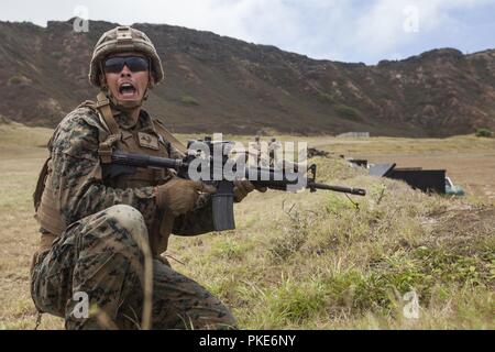 Us Marine Lance Cpl. Wyatt Prettyman, einem truppführer mit Lima Company, 3.BATAILLON, 3. Marine Regiment, III Marine Expeditionary Force, brüllt Befehle bei Fire team Angriff an der Kaneohe Bay Bereich Training Service, Marine Corps Base Hawaii, 26. Juli 2018. Riflemen nutzten ihre individuelle Waffensysteme wie der M203 Granatwerfer, M72 Licht Panzerabwehr: Waffe (Gesetz), M4A1 Assault Rifle und das M27 Sturmgewehr Infanterie ein Brand Team Assault zu führen. Marines mit Indien, Kilo und Limo Unternehmen zusammen gearbeitet, ihre Kommunikation, Führung und Letalität als Feuer zu verbessern. Stockfoto