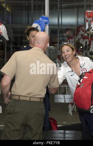 Us Marine Corps Oberst Richard F. Fuerst, der kommandierende Offizier der Marine Corps Air Station Iwakuni, begrüßt Heather Tarr, behilflicher Trainer für nationale Softball Team der USA Frauen, die iwakuni Kintaikyo Flughafen Stadt Iwakuni, Japan, 27. Juli 2018. Die USA Women National Softball Team Iwakuni Stadt reiste für die bevorstehenden Olympischen Spiele mit dem neuen Stadion Kizuna zu trainieren. Das Stadion ist ein Markenzeichen von, was die US-japanischen Freundschaft in Iwakuni Stadt vollbracht hat. Stockfoto