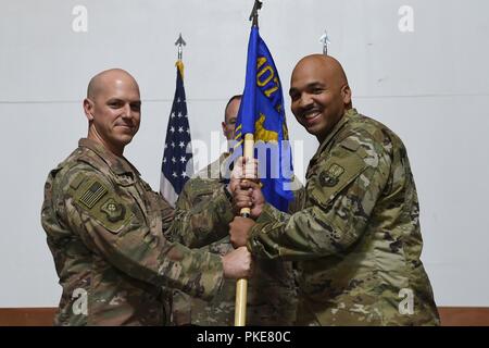 Oberst Scott Gibson, 407 Air Expeditionary Gruppenkommandant und Presiding Officer, präsentiert die 407 Expeditionary Bauingenieur Squadron guidon, Maj. Shane Patty bei einem Befehl Zeremonie an einem geheimen Ort im Südwesten Asien, 27. Juli 2018. Oberstleutnant Glenn Cameron Befehl des Geschwaders an Patty während der Zeremonie verzichtet. Stockfoto