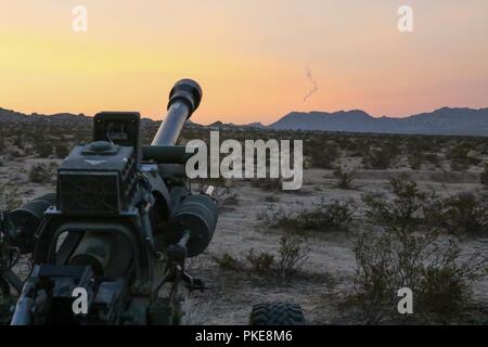 Eine Beleuchtung runden vom 2 Bataillon abgefeuert, 218. das Feld Artillerie M119 Haubitze setzt mit der Sonne Juli 27, 2018 Während ein Feld Training als exportierbar Combat Training (XCTC) in Fort Irwin, Kalifornien bekannt. Die Übung ist ein radlager Brigade Feld Training konzipiert Platoon Kenntnisse über die Feuerwehr in Abstimmung mit der ersten Armee zu zertifizieren. "Diese Übung hält unsere Einheiten ausgebildet und bereit für Missionen und baut auf der Ausbildung des Brigade aus dem letzten Jahr Warfighter Übung", sagte Oberst Eric Riley, Kommandant der 41 IBCT. Stockfoto