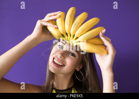 Fröhliche junge Frau mit Bananen headwear auf lila Hintergrund. Stockfoto