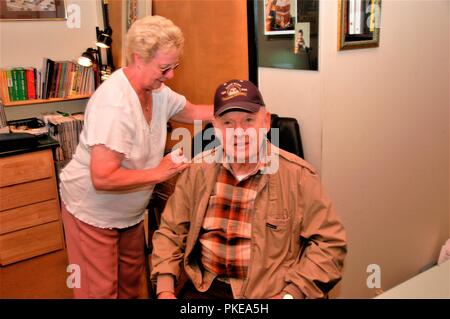 Senior real Paar, wo er Hilfe benötigt von ihr und Hilfe im Alltag mit Walker und an seinem Standort noch am 88 Stockfoto