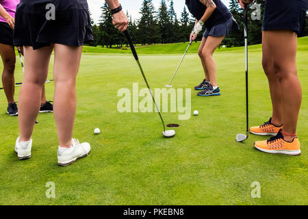 Ein viererspiel der weiblichen Golfspieler auf dem Putting Green, Putting über die beste Kugel in einem Texas Scramble während eines Turniers Stockfoto