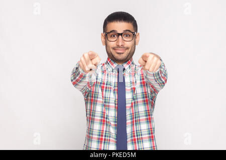 Hey ihr. Portrait von Happy bearded Geschäftsmann in bunt kariertem Hemd, blaue Krawatte und schwarze Brillen stehen und zeigen auf Kamera mit Lächeln. Stockfoto