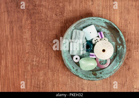 Ein Foto von verschiedenen Perlen und Knöpfen in einer kleinen Teal Blue Platte, mit Kopie Raum Stockfoto