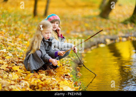 Süße kleine Mädchen, die durch das Wasser auf der herrlichen Herbsttag. Glückliche Kinder Spaß im Herbst Park. Herbst Aktivitäten für Kinder. Stockfoto