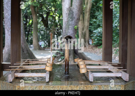 Ein Brunnen mit Bambus Schöpfkellen für rituelle Reinigung vor dem Betreten der Meiji Schrein in Tokio Stockfoto