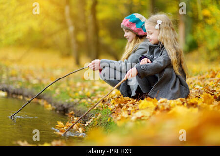 Süße kleine Mädchen, die durch das Wasser auf der herrlichen Herbsttag. Glückliche Kinder Spaß im Herbst Park. Herbst Aktivitäten für Kinder. Stockfoto