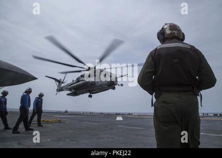 MINDANAO MEER - U.S. Navy Segler mit der Essex Amphibious Ready Group (ARG) und Marines mit dem 13 Marine Expeditionary Unit (MEU) bereiten Sie eine CH-53E Super Stallion mit Marine Medium Tiltrotor Squadron 166 verstärkt, 13. MEU, für Abflug an Bord der Wasp-Klasse amphibisches Schiff USS Essex (LL 2) während der Durchführung von Such- und Rettungsaktionen während einer planmäßigen Einsatz der Essex ARG und 13. MEU, 11. August 2018. Das Essex ARG/13 MEU ist derzeit auf dem Siebten Flotte Bereich der Operationen eingesetzt. (U. Us Marine Corps Stockfoto