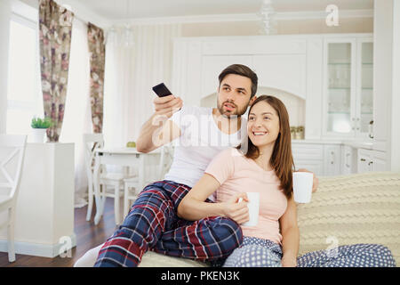 Ein Mädchen und ein Kerl Fernsehen sitzen auf dem Sofa im Zimmer. Stockfoto