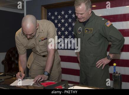 NEWPORT NEWS, Virginia (Aug. 1, 2018) Lt. j.g. Zachary Klassen, von Phoenix, auf USS Gerald R. Ford's (CVN 78) Waffen Abteilung zugewiesen, Zeichen seiner Lieferung der ständigen Termin Schreibarbeit während der Werbeaktion Zeremonie an Bord Ford. Stockfoto