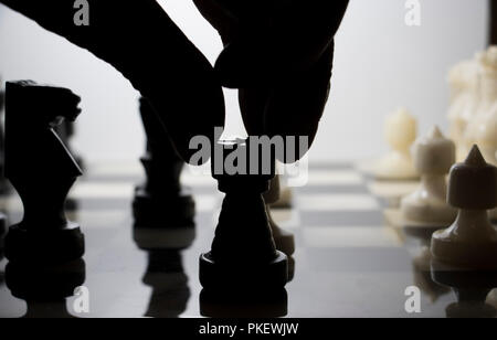 Hand in silhouette Schach zu spielen. Bewegliche Figuren auf einem Schachbrett. Stockfoto