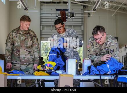 Spec. Derek Preis, Pfc. Joshua Taulaga und Spec. Austin Miller mit dem 176 Ingenieur Unternehmen Vorräte der neuen Ausrüstung, die Sie vor dem Gehen zu helfen wildfires Beeinträchtigung der Eastern Washington, Mittwoch, Aug 1, 2018 in Camp Murray, Washington Kampf erhalten. Die 176. ordnete im Camp Murray den Prozess der Wechsel in den Zustand Active Duty zu beginnen. Stockfoto