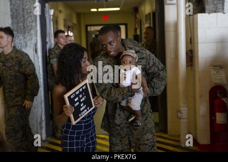 Us Marine Cpl. Delaurence Harmon grüßt seine Familie nach der Rückkehr nach Hause von sieben - Monat Bereitstellung mit dem 26 Marine Expeditionary Unit (MEU) bei Marine Corps Air Station Cherry Point, N.C., am 2. August 2018. Marines wurden von ihren Familien, Freunden und Lieben zu den VMA-542 Hangar. Harmon ist ein Flugzeug Avionik tech mit VMA-542, Marine Flugzeuge Gruppe 14, 2. Marine Flugzeugflügel. Stockfoto