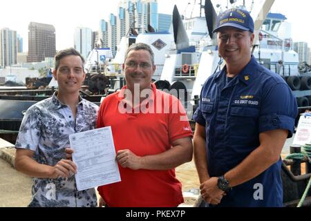 Die Eigentümer des Schiffes Namahoe erhalten neue des Schiffes Kontrollbescheinigung, die Ihnen von Chief Warrant Officer Bryan Anderson in Honolulu, Aug 2, 2018 ausgestellt. Die Kontrollbescheinigung war die erste in der Coast Guard 14. Bezirk nach der Umsetzung der neuen Vorschriften, 20. Juli 2018 ausgestellt werden. Stockfoto