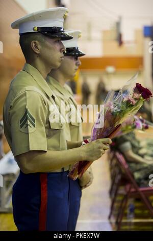 Cpl. Barry Kuang hält einen Strauß Blumen während einer Post- und Überdruckventil Zeremonie auf der Marine Corps Air Station Futenma, Okinawa, Japan, August 2, 2018. Sgt. Maj Daniel Heider erleichtert, Sgt. Maj. Jason Hängematte als Sergeant Major für MACS-4. Kuang, aus New York City, ist ein Air traffic control radar Techniker. Stockfoto