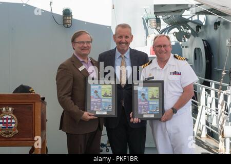 SEATTLE (4. August 2018) Michael Wuff, Konsul und Leiter der für Handel zuständige Kommissar an das Generalkonsulat von Kanada in Seattle; Seafair Präsident und CEO Richard Anderson; und Kapitän Steve Jorgensen, stellvertretender Kommandant der Kanadischen Flotte Pacific, posieren für ein Foto mit commemorative Drucke der 2018 Seattle Seafair Poster bei einem Empfang an Bord Kingston gehalten - Klasse Küstenschutz Schiffe HMCS Whitehorse (710) und HMCS Yellowknife (706) Seattle Seafair Flotte während der Woche. Seafair Fleet Week ist eine jährliche Feier des Meeres Dienstleistungen darin Seemänner, Marinesoldaten und Küstenwache, Mitglieder von visi Stockfoto