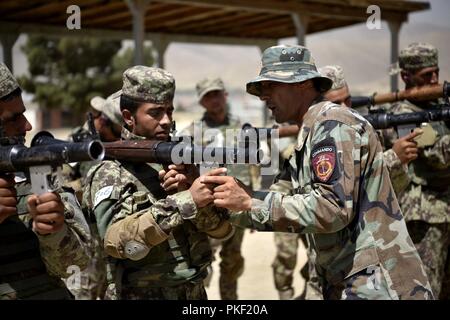 KABUL, Afghanistan (2. August 2018) - ein Afghan National Army Special Operations Command (ANASOC) School of Excellence (SOE) Waffen Kursleiter Gespräche Commando Rekruten durch die Grundsätze der Rakete selbstfahrende Grenade-Seven (RPG-7) in Kabul, Afghanistan, 2. August 2018 das Feuern. Während einer Woche von Anweisung, 770 Rekruten erhielt eine Ausbildung und jeder Schüler feuerte ein bis zwei Mal. In den kommenden Wochen Rekruten Übergang in Phase Zwei, der Fokus verschiebt sich von Individuum zu Teamfähigkeit, wie Security Patrol, Nacht Missionen und Close Quarters Battle (CQB). (NATO Stockfoto