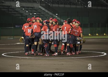 Mitglieder der japanischen Toyota Red Terrier Softballmannschaft stehen auf der einen Krug Damm während ein Softball Spiel in Stadt Iwakuni, Japan, 31. Juli 2018. Die rote Terrier konkurrierten gegen die Nationalmannschaft der USA Softball Frauen besuchte Marine Corps Air Station Iwakuni und Iwakuni Stadt, um für die World Baseball Softball Eidgenossenschaft (WBSC) Weltmeisterschaft der Frauen, wo sie geplant sind für einen Platz in der Olympischen Spiele 2020 in Tokio, Japan zu konkurrieren. Stockfoto