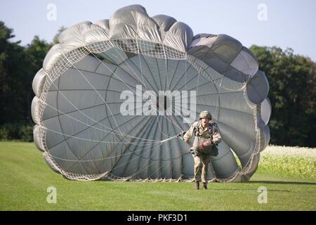 Eine britische Fallschirmjäger läuft zum X auf Schloss Drop Zone mit seinem MC-6 Fallschirm während Leapfest 2018 West Kingston, RI., 5. August 2018. Leapfest ist der größte und am längsten bestehende, internationale statische Linie Fallschirm Training und Wettbewerb veranstaltet vom 56. Truppe den Befehl, Rhode-Island Army National Guard hohe technische Ausbildung zu fördern und Korpsgeist innerhalb der internationalen Gemeinschaft in der Luft. Stockfoto