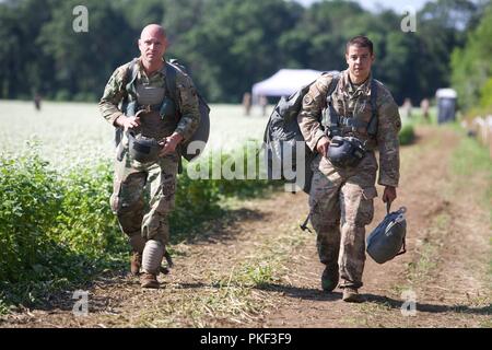 Zwei US-Armee Fallschirmjäger trägt ihre MC-6 Fallschirme aus der Burg Drop Zone nach einem Sprung in der Luft während Leapfest 2018 West Kingston, RI., 5. August 2018. Leapfest ist der größte und am längsten bestehende, internationale statische Linie Fallschirm Training und Wettbewerb veranstaltet vom 56. Truppe den Befehl, Rhode-Island Army National Guard hohe technische Ausbildung zu fördern und Korpsgeist innerhalb der internationalen Gemeinschaft in der Luft. Stockfoto