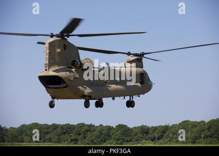 Ein U.S. Army CH-47 Chinook Hubschrauber, Bravo Company, 2-104 th GSAB, 28 Combat Aviation Brigade zugeordnet, zieht aus der Zone Wählen Sie eine Gruppe von Fallschirmjägern während Leapfest 2018 West Kingston, RI., 5. August 2018 auf Schloss Drop Zone zu fallen. Leapfest ist der größte und am längsten bestehende, internationale statische Linie Fallschirm Training und Wettbewerb veranstaltet vom 56. Truppe den Befehl, Rhode-Island Army National Guard hohe technische Ausbildung zu fördern und Korpsgeist innerhalb der internationalen Gemeinschaft in der Luft. Stockfoto