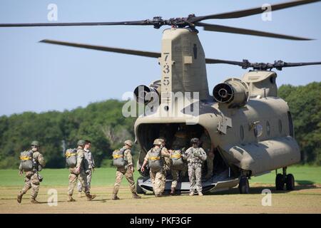 Eine Gruppe von US-Soldaten und Britische Fallschirmjäger bereiten Sie eine CH-47 Chinook Hubschrauber auf dem Pick Up Zone Board während Leapfest 2018 West Kingston, RI., 5. August 2018. Leapfest ist der größte und am längsten bestehende, internationale statische Linie Fallschirm Training und Wettbewerb veranstaltet vom 56. Truppe den Befehl, Rhode-Island Army National Guard hohe technische Ausbildung zu fördern und Korpsgeist innerhalb der internationalen Gemeinschaft in der Luft. Stockfoto