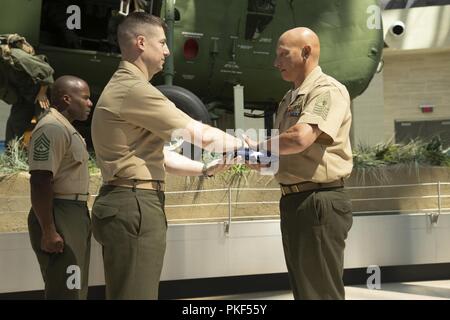 Us Marine Corps Maj. Jonathan Zarling, Links, stellvertretender Leiter, Manpower Management Soldaten Zuordnung (MMEA), präsentiert die amerikanische Flagge zu Master Gunnery Sgt. Cody Abel, Monitor, MMEA, an dem Nationalen Museum der Marine Corps, Dreieck, Virginia, 27. Juli 2018. Abel diente 20 Jahre Damen und Gläubigen der Wehrdienst. Stockfoto