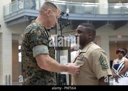 Us Marine Corps Oberstleutnant Joel Schmidt, Operations Officer, Marine Corps Taktik und Operations, präsentiert die Meritorious Service Medal zu Master Sgt. Marcus Gold, Bataillon Operations Chief, SEK BN, an dem Nationalen Museum der Marine Corps, Dreieck, Virginia, 27. Juli 2018. Gold diente 20 Jahre Damen und Gläubigen der Wehrdienst. Stockfoto