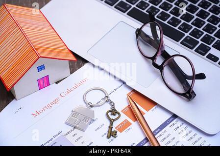 Schlüssel mit Stift und Haus Modell und Gläser auf Notebook lag auf mortage Dokument, Finanzen Konzept. Stockfoto