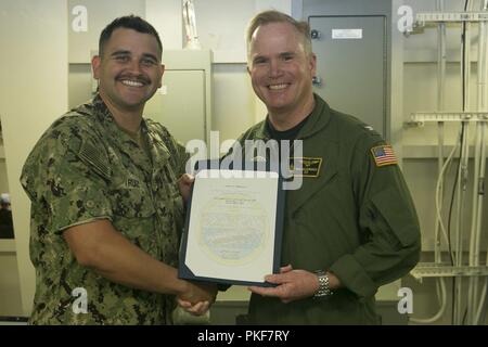 NEWPORT NEWS, Virginia (Aug. 9, 2018) Mass Communication Specialist 2. Klasse Kristopher Ruiz, von Kansas City, Missouri, auf USS Gerald R. Ford's (CVN 78) Medien Abteilung zugewiesen, erhält ein Lob von Kapitän Richard McCormack, Ford's kommandierenden Offizier, für seine Auswahl als Petty Officer's Ford des Quartals. Stockfoto