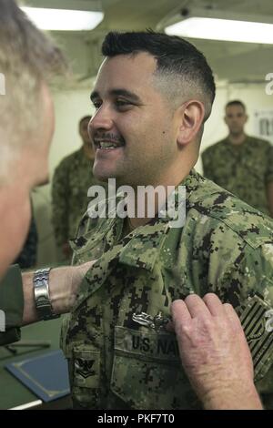 NEWPORT NEWS, Virginia (Aug. 9, 2018) Mass Communication Specialist 2. Klasse Kristopher Ruiz, von Kansas City, Missouri, auf USS Gerald R. Ford's (CVN 78) Medien Abteilung zugewiesen, erhält seine Soldaten Oberfläche Kriegsführung Spezialist Stift von Kapitän Richard McCormack, Ford's kommandierender Offizier. Stockfoto